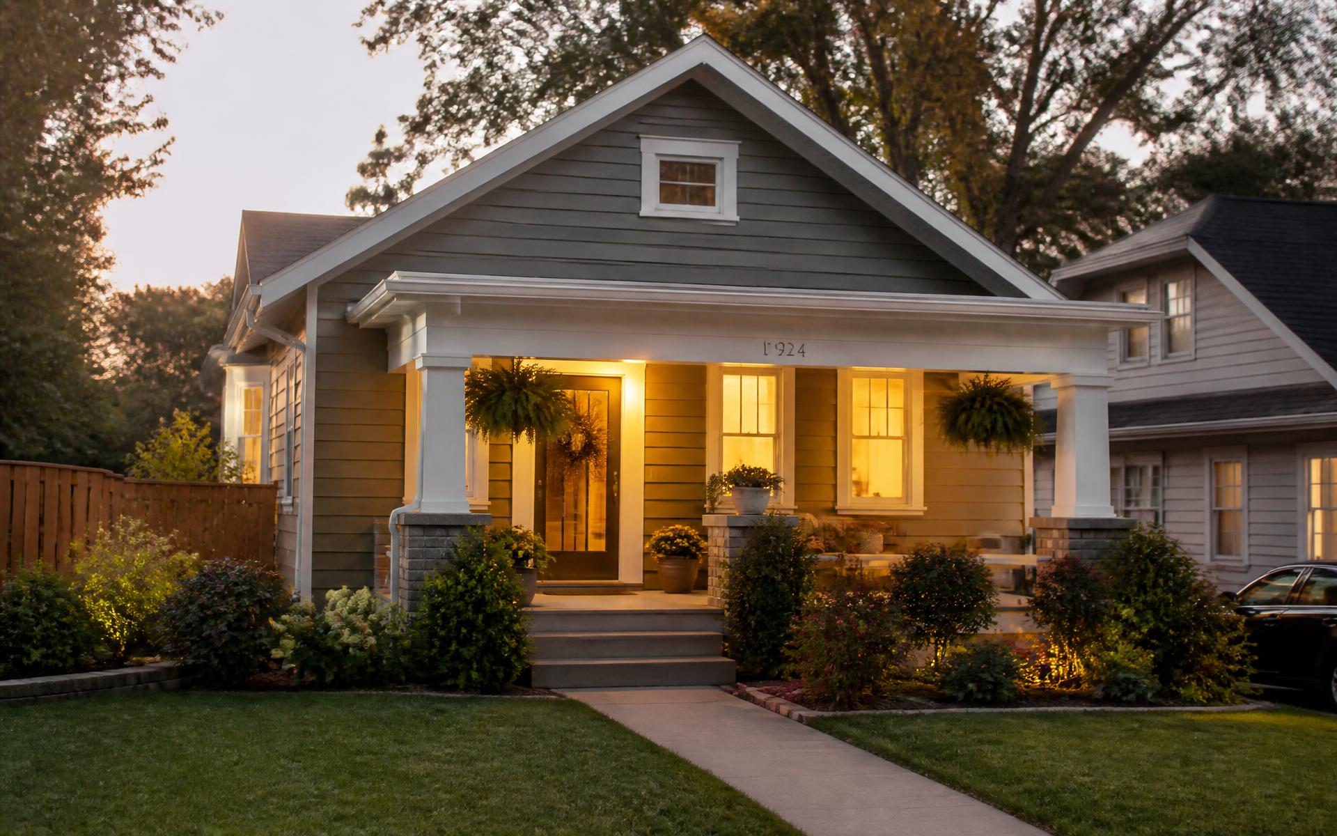 A welcoming, well-kept home with porch lights on at dusk